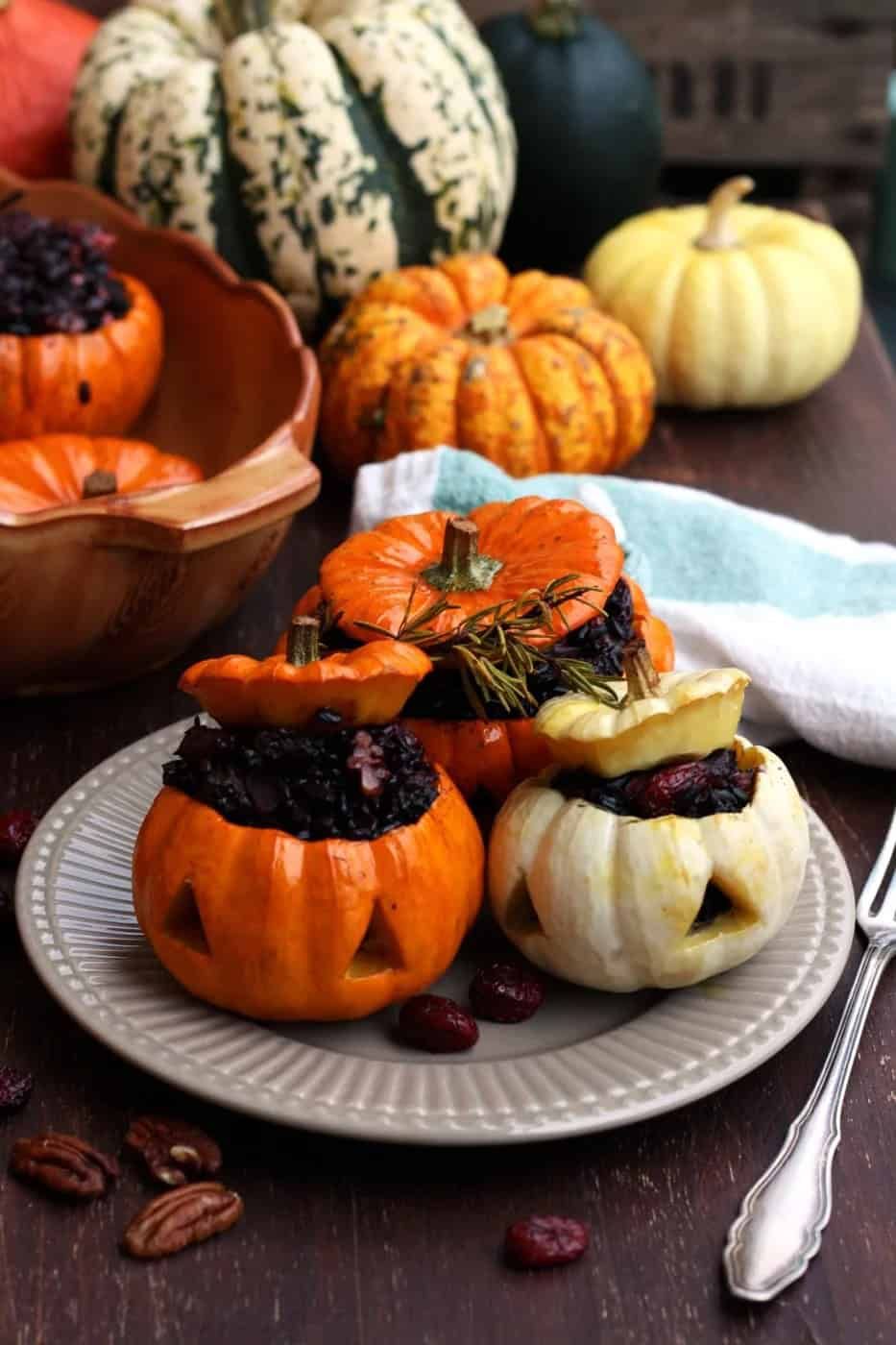 Roasted mini pumpkin halves filled with seasoned rice, cheese, and black bean “spider” garnish on a rustic board
